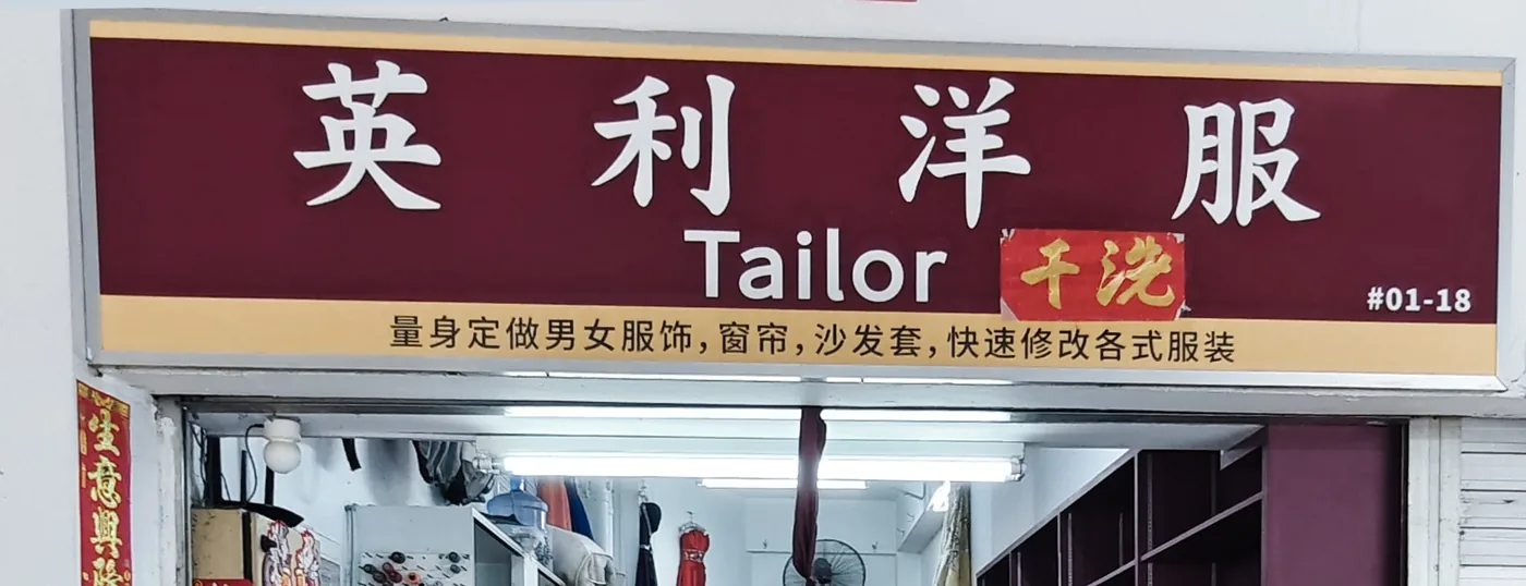 Crop of the YL Clothes signboard reading 英利洋服 Tailor 干洗, with the text 量身定做男女服饰，窗帘，沙发套，快速修改各式服装